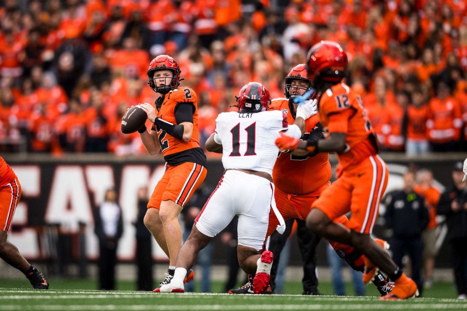 Braden Atkinson setting up to pass in an orange Oregon State uniform with the Reser Stadium crowd behind him