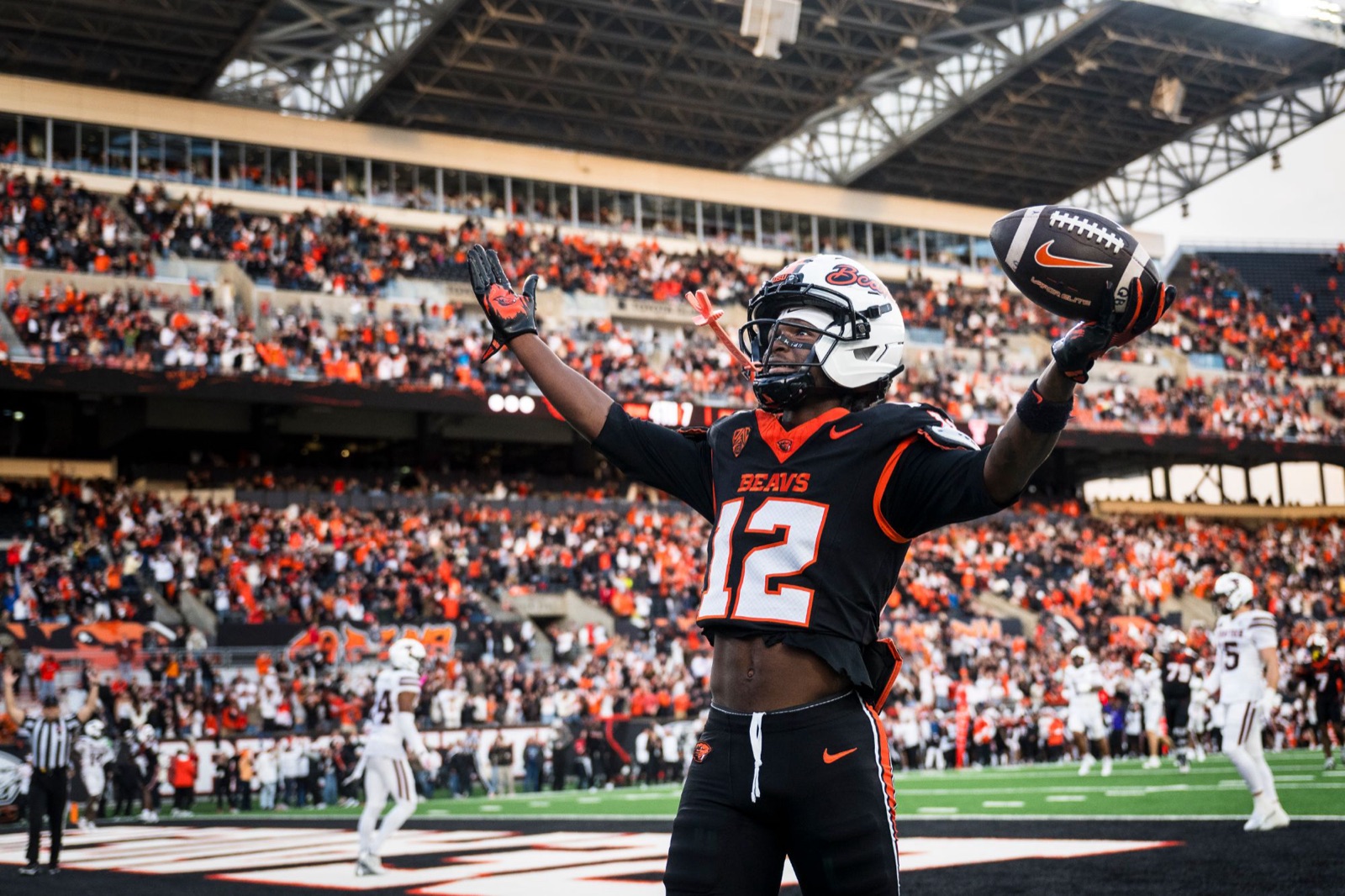 Jesse Legree raising his arms and the football in the end zone as Reser Stadium cheers